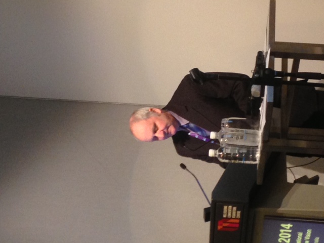 Neil Jarvis presenting at a conference, speaking at a podium with a microphone